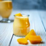 A small glass cup filled with yellow smoothie