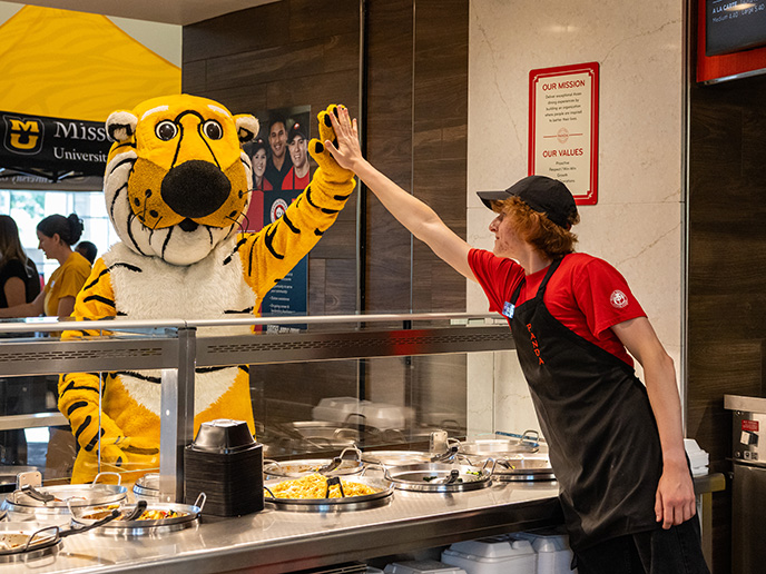 A Panda Express employee giving Truman the Tiger a high-five